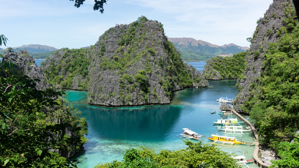 Limestone islands surrounded by deep blue ocean water and boats in Coron, Philippines.