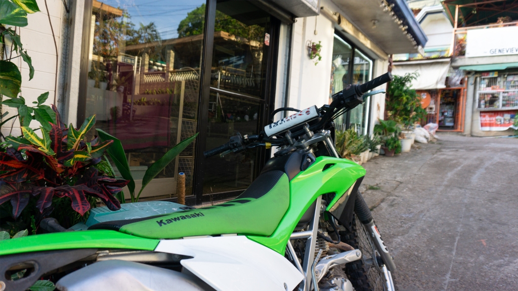 A green and white motorbike sitting in front of a shop in Coron Town in the Philippines.