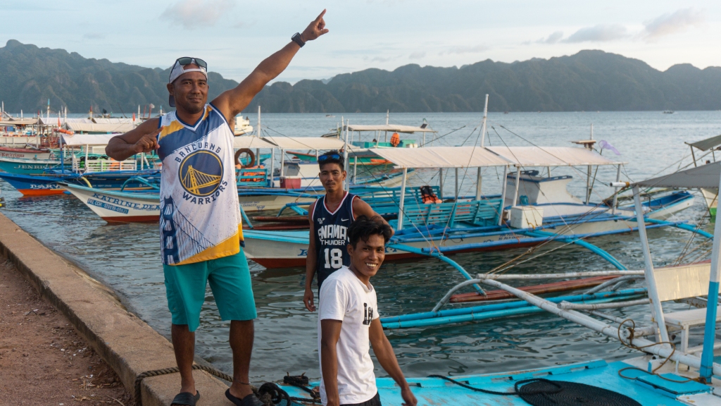 Three men from the Philippines standing on a boat dock in Coron, Palawan.