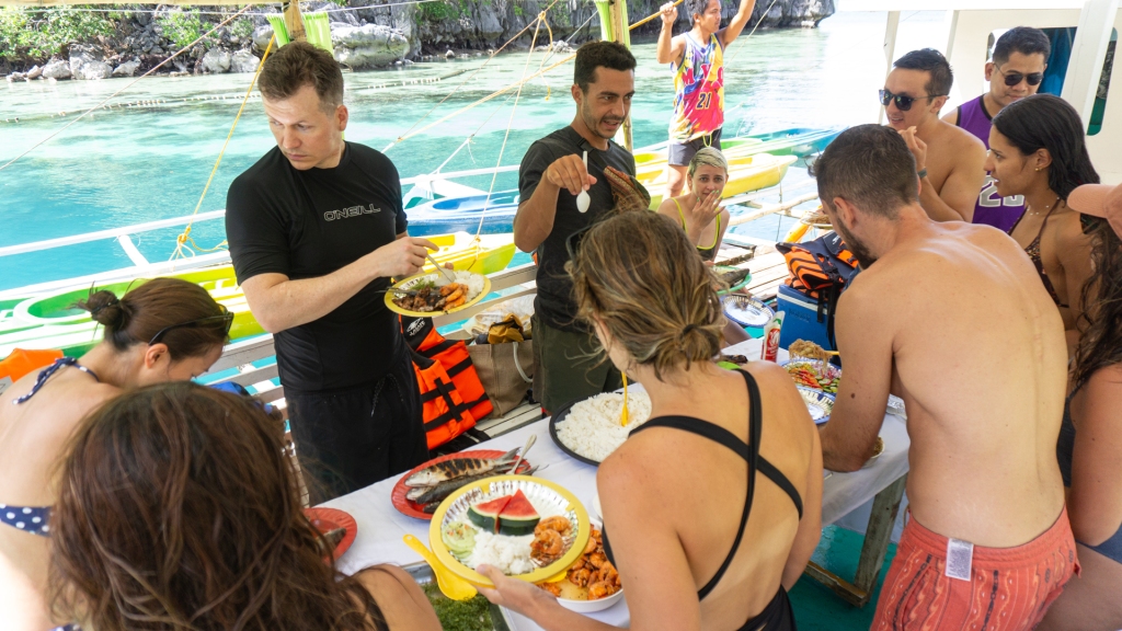 A group of people eating a lunch buffet on a small boat in the Philippines.