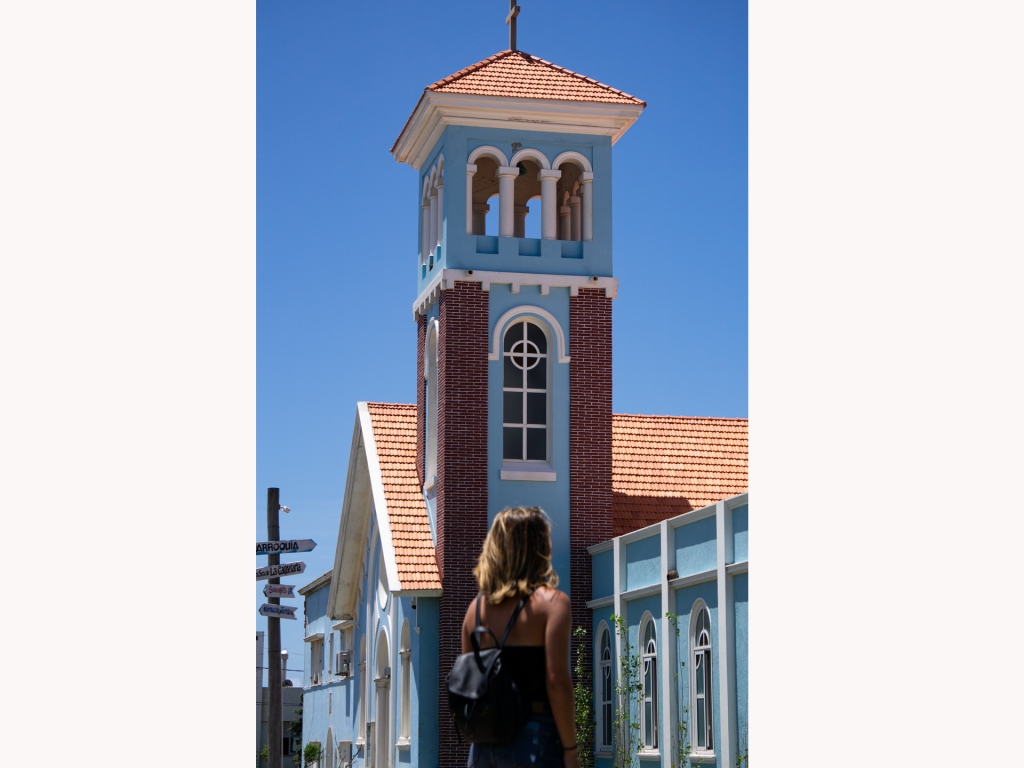 A woman standing in front of an old blue church in Punta del Este, Uruguay.